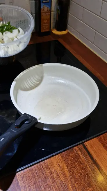 Sautéing the prepared sliced onions and chilies in the oiled wok