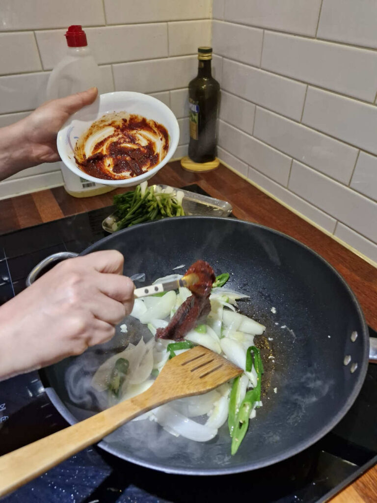Adding the red sauce to the pan