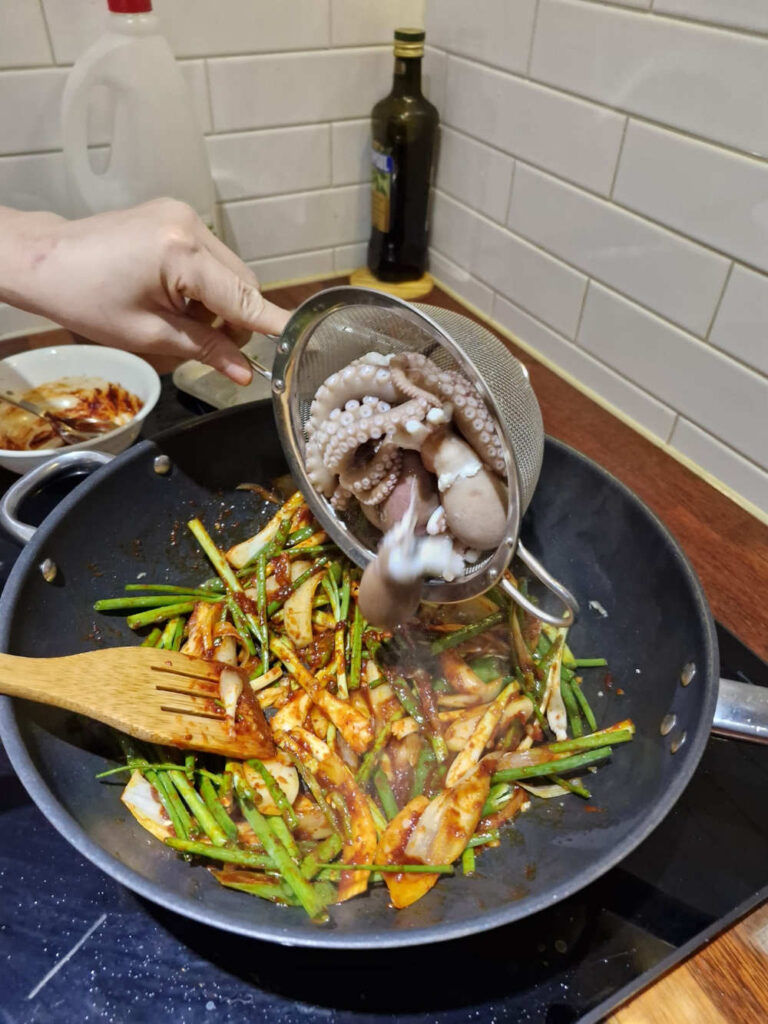 Adding octopus to the sizzling pan