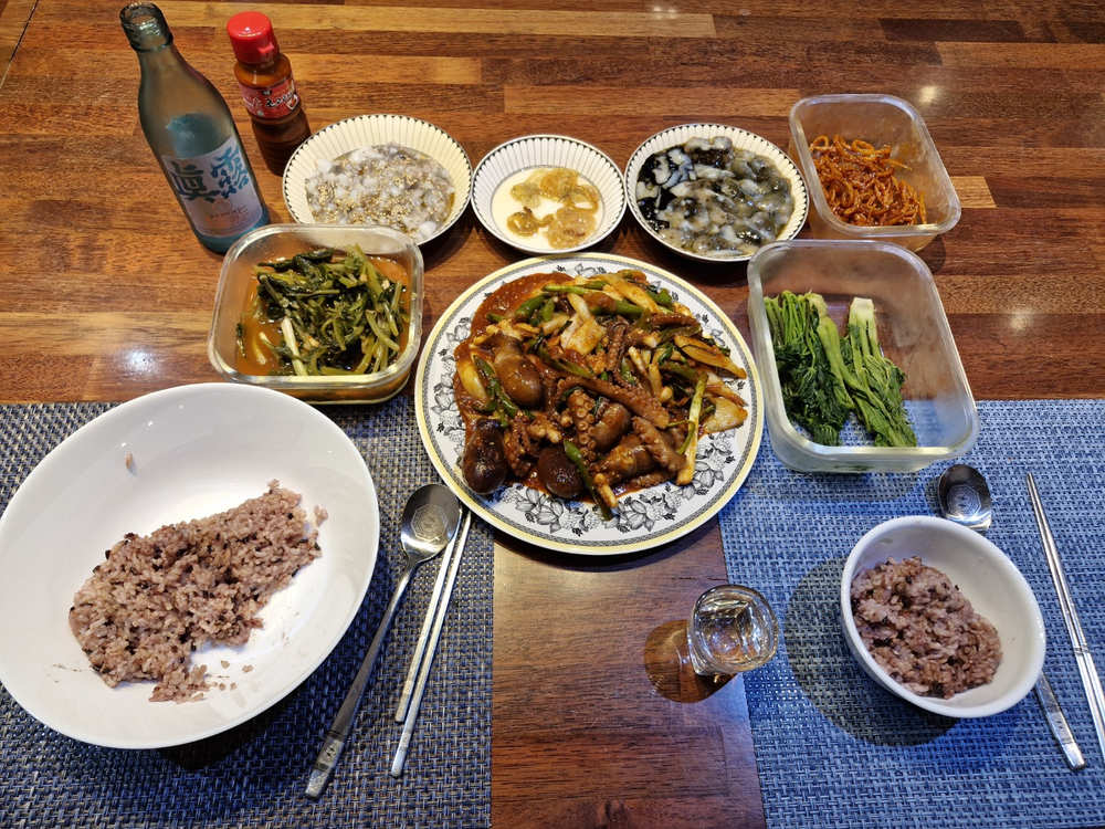 A vibrant, full-table shot of Nakji Bokkeum served with rice and side dishes