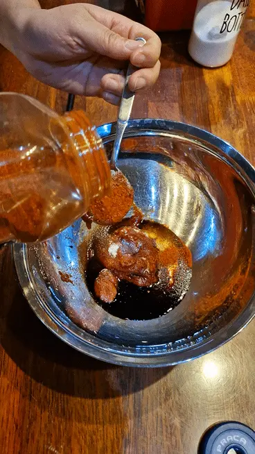 Spoonful of red Gochugaru (Korean chili flakes) being added for heat