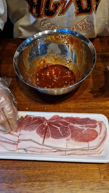 Submerging thinly sliced pork shoulder into the finished red Jeyuk marinade