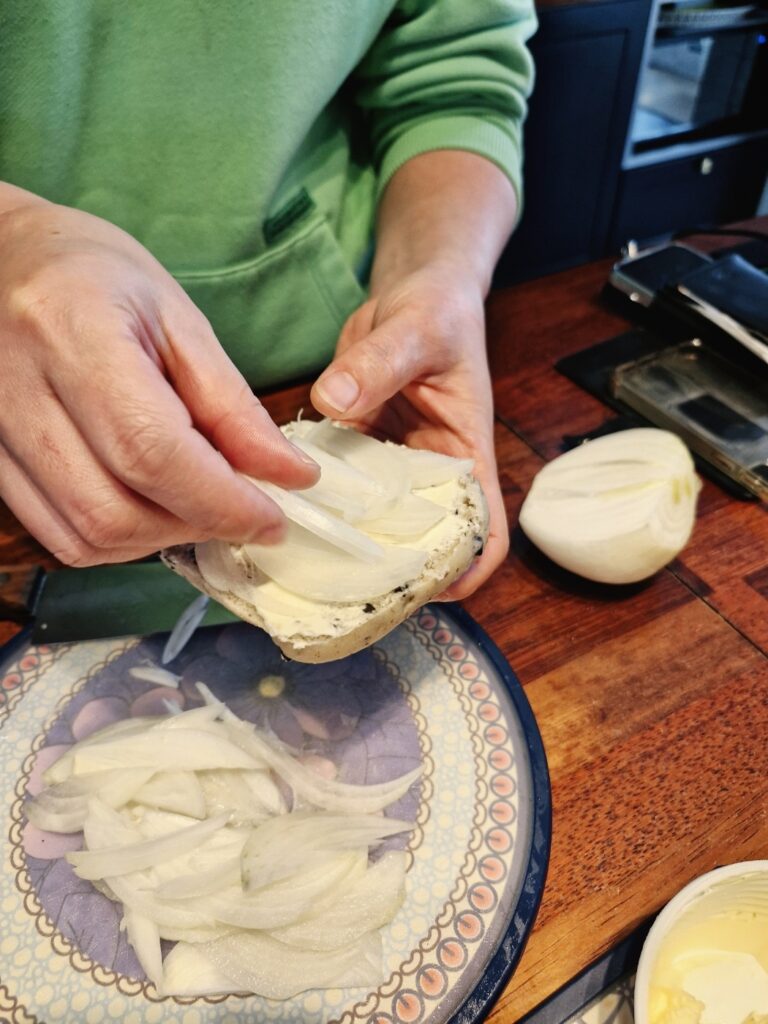 Layering cured salmon on onions and sprinkling black pepper
