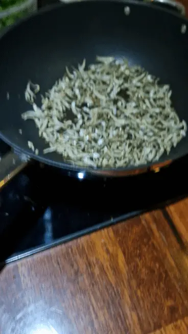 Adding cooking oil to roasted anchovies and stir-frying