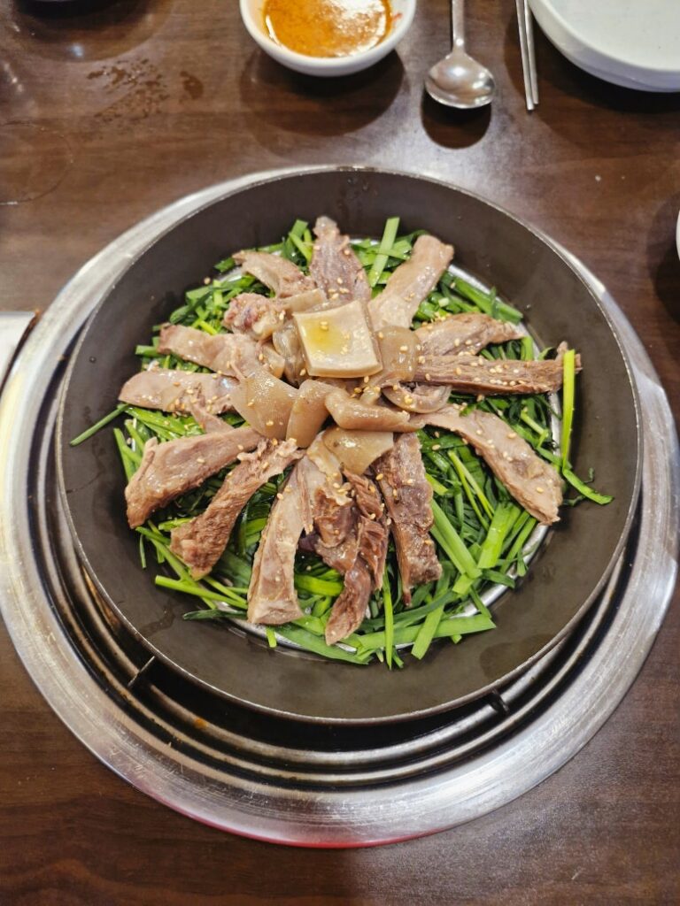 Tender steamed black goat meat (Suyuk) served over a bed of fresh chives.