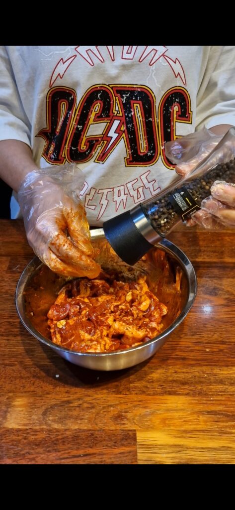 Grinding fresh black pepper over the already marinated Jeyuk pork