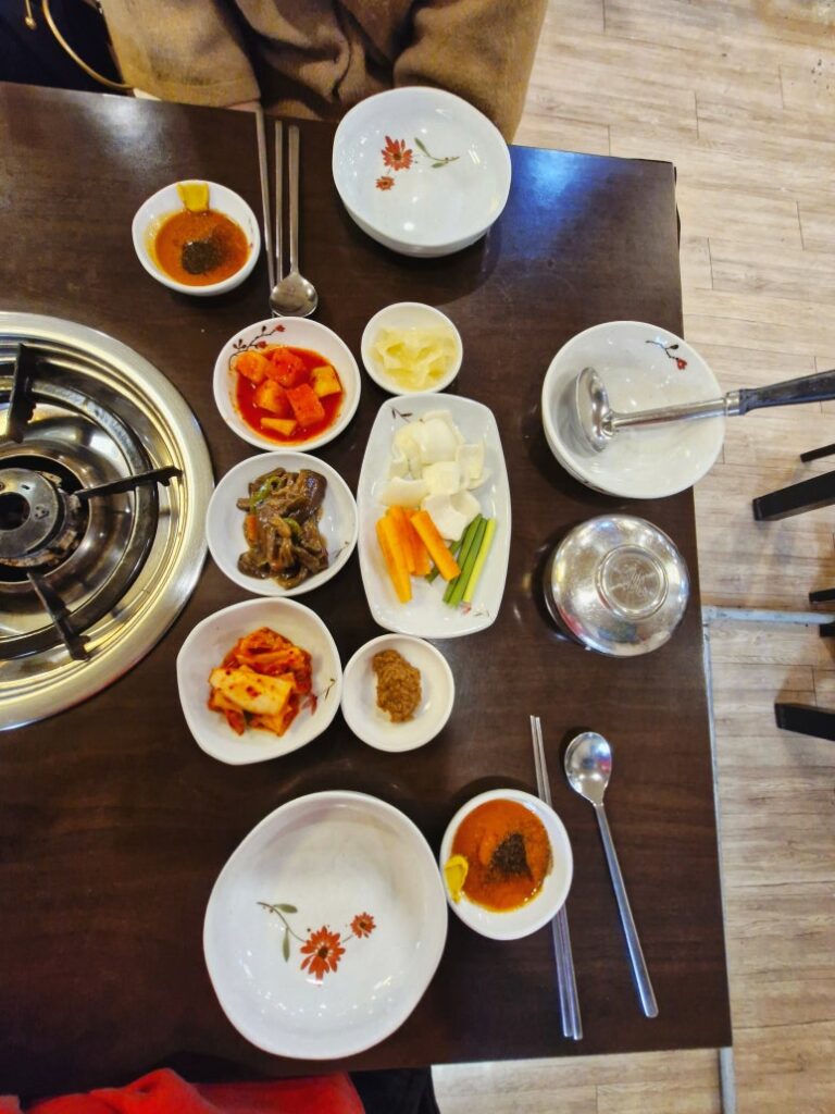 Traditional Korean side dishes including kimchi, eggplant, and fresh ginger.