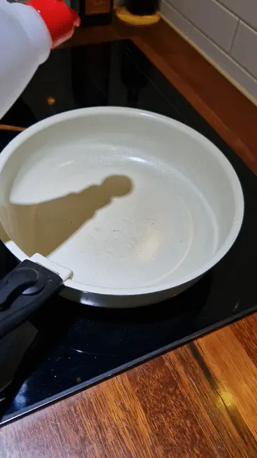 Pouring cooking oil onto a hot, dark wok