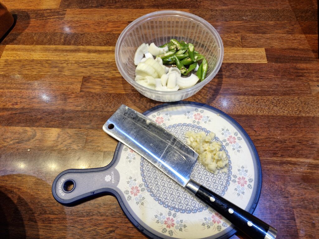 Prepared chopped onions, sliced chilies, and crushed garlic in separate bowls