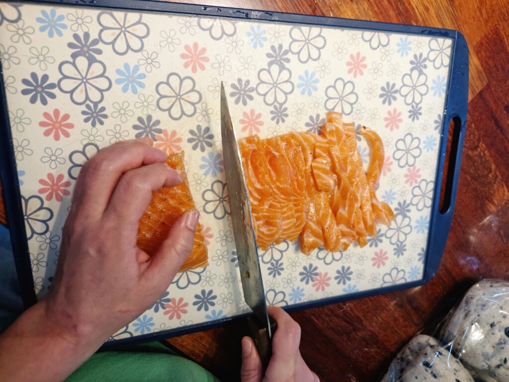 Slicing the firm, cured salmon into thin pieces