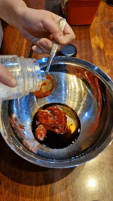 Sprinkling white sugar over the developing Jeyuk seasoning