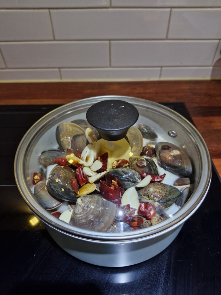 Covering the pot with a lid to steam the clams in beer and butter broth.