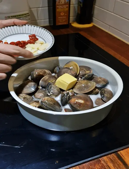 Adding a knob of butter and sliced garlic to the pot of clams and beer.