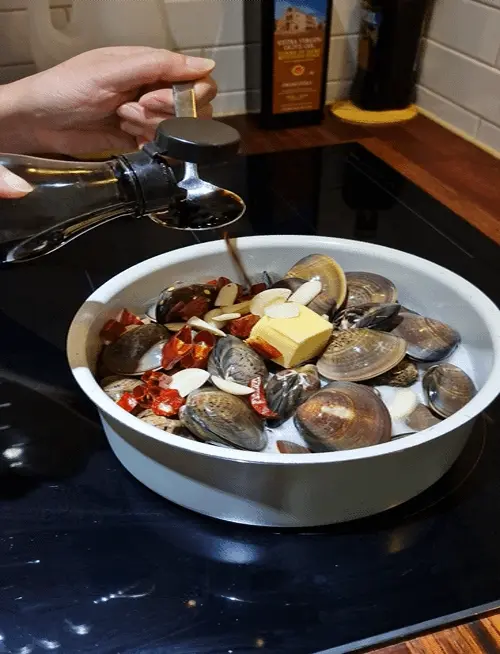 Adding a knob of butter and sliced garlic to the pot of clams and beer.