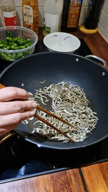 Stir-frying dried anchovies in a dry pan over medium heat