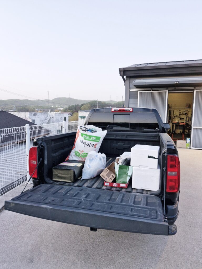 A Chevy Colorado truck bed filled with recycling bags and garbage.