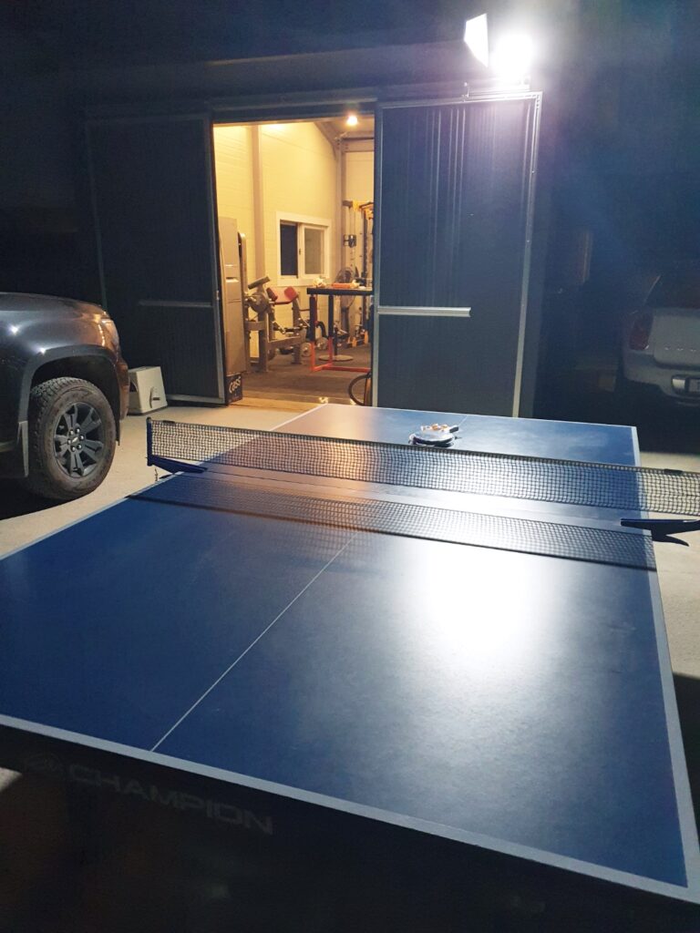 A full-sized table tennis table being unloaded from a Chevy Colorado.