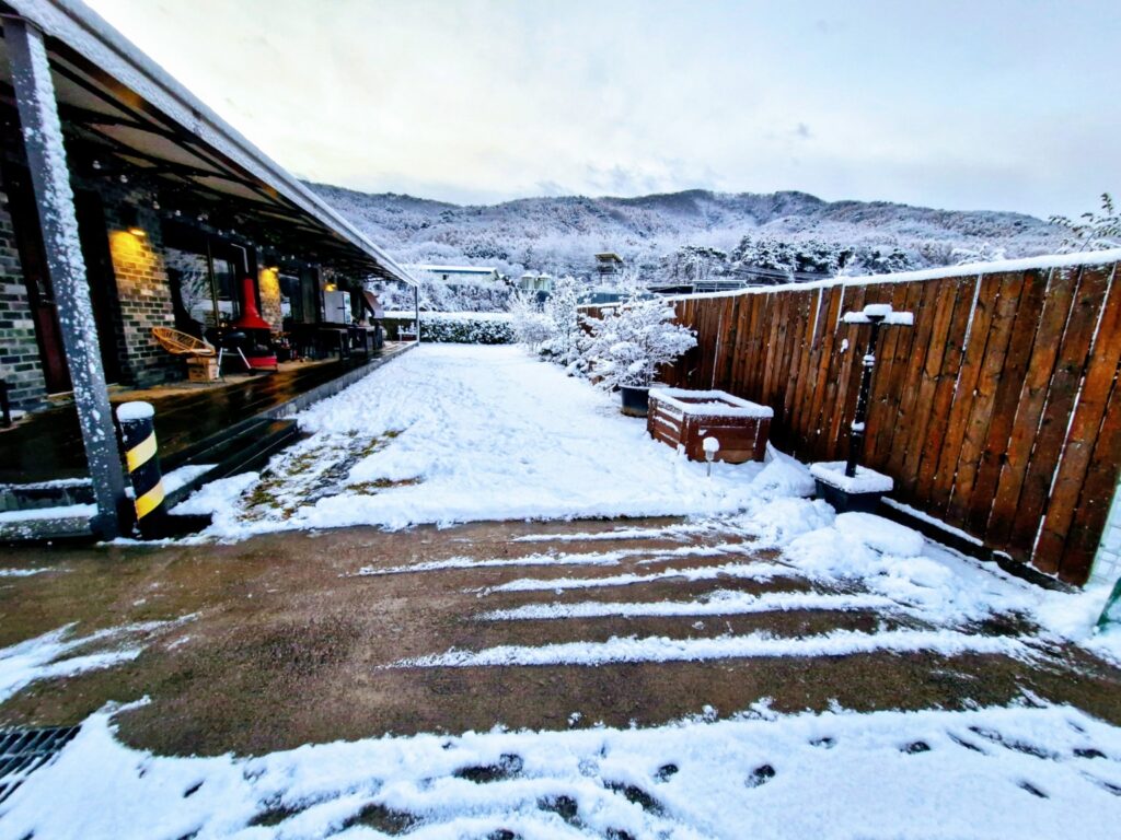 A snowy winter landscape of a countryside garden and mountains in Paju, showing the frozen scenery before the Spring in Korea.